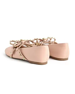 Detailed rear view of nude pink round-toe ballet flats featuring a studded bow strap
