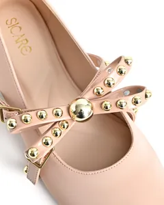 Close-up of pink flat shoes featuring gold stud bow detail and buckle.