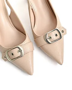 Dettaglio di eleganti décolleté beige a punta con fibbia e una texture coccodrillo.