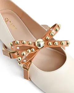 Close-up of elegant cream round-toe ballet flats with a studded brown bow and gold buckle.