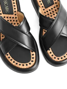 Detailaufnahme der schwarzen Sandalen mit Kreuzriemen und einem Kork-Massagefußbett.