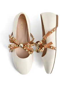 Macro detail of cream ballet flats featuring studded brown straps and gold buckles