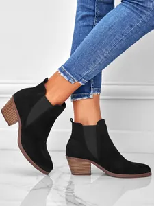 Side view of black suede pointed toe ankle boots with chunky wooden heels on model