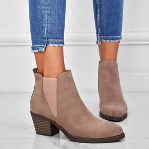 Close-up detail of stylish taupe suede ankle boots with chunky heel and elastic panels