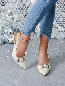 Dettaglio scarpe beige a punta con fibbia in metallo e texture effetto coccodrillo