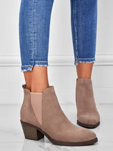 Detail of women's taupe suede ankle boots with chunky heels and blue jeans