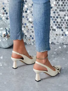 Vista laterale di eleganti tacchi slingback bianchi con coccodrillo e fibbia chic.