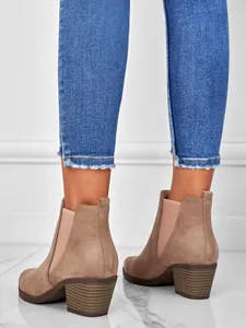 Detailed rear view of stylish tan suede chunky heel ankle boots worn with blue jeans