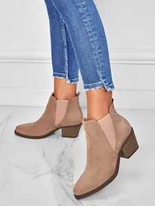 Close-up detail of women's taupe suede ankle boots with block heel and pointed toe.