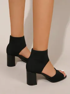 Close-up view of elegant black breathable fly-knit open-toe sandals with a sturdy block heel