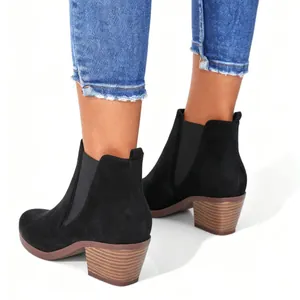 Women's black suede Chelsea ankle boots with block heel, worn with denim jeans