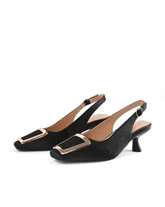 Close-up detail of black crocodile-embossed slingback kitten heels featuring a gold buckle