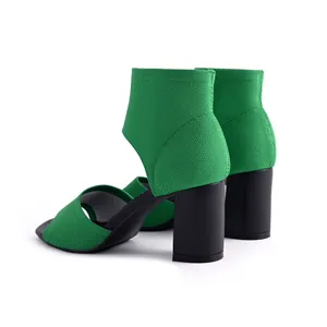 Detailed view of green fly-knit fabric and black block heel of summer peep-toe sandals