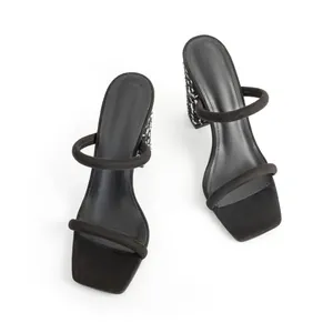 Detail view of black square-toe sandals with chunky heels and double strap design.