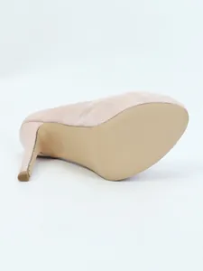 Detailed close-up showing the sole and high stiletto heel of a beige suede platform pump.