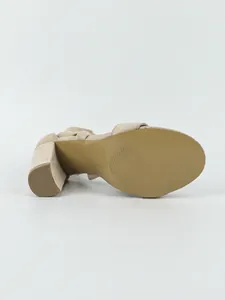 Detailed bottom view showing the non-slip sole and chunky block heel of a beige suede sandal