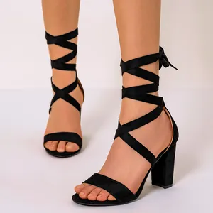 Close-up of stylish black suede block heel sandals with elegant lace-up cross straps