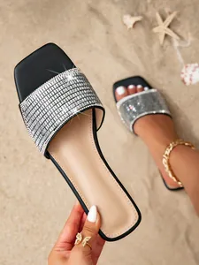 Close-up detail of women's black square toe flat sandals with shimmering silver rhinestone band