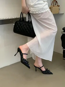 Close-up view of elegant polka dot pointed toe stiletto mules with a bow worn by a model