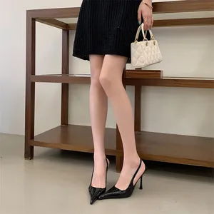 Elegant black pointed toe slingback pumps with slim stiletto heels worn by model