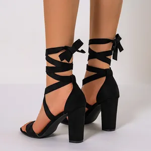 Detail view of black suede lace-up high heel sandals with elegant ankle bows.