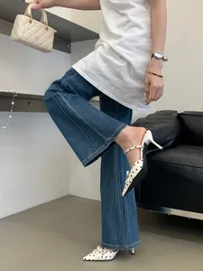 Close-up of white polka dot bow pointed toe high heel mules worn with denim jeans.