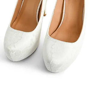 Close-up detail of white lace floral texture on elegant platform high heel pumps.