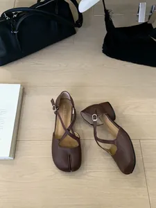 Detailansicht brauner Mary Jane Schuhe mit Tabi-Zehen und Kreuzriemen auf Holzboden