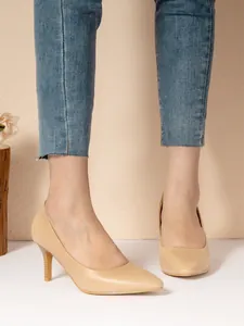 Close-up of elegant apricot pointed-toe stilettos paired with blue jeans