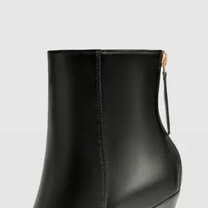 Detail view of black stiletto boot showing back zipper and golden hardware