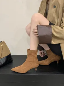 Detalle de botines de ante marrón con punta afilada y tacón de aguja en modelo