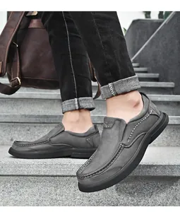 Grijze herenleren loafers met contrasterende stiksels op stenen buitentrappen