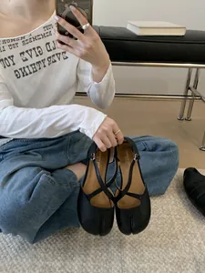 Detaillierte Nahaufnahme der schwarzen Tabi-Sandalen mit geteilten Zehen und Kreuzriemen.