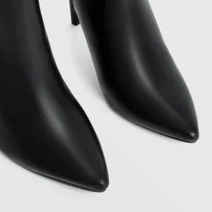 Close-up detail of sleek black leather pointed-toe fashion boots with high stiletto heels.