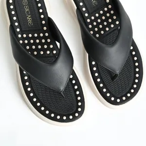 Close-up of black platform flip-flops featuring a white massage node footbed detail