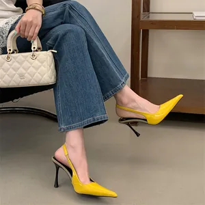 Yellow pointed-toe slingback high heels in patent leather worn by a model in a casual setting.