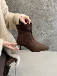 Primer plano de botines de ante marrón con punta afilada y elegantes tacones.