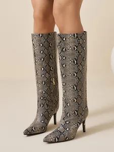 Detailed view of snake print knee-high boots with pointed toe and stiletto heel