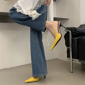 Close-up of stylish yellow pointed-toe slingback high heels worn with denim jeans.