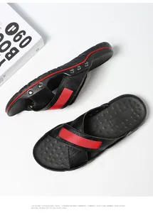 Detail van zwarte leren heren strandsandalen met een rode streep en metalen noppen