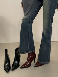Hochwertiges Detail französischer Stiletto-Stiefeletten aus schwarzem und burgunder Lackleder