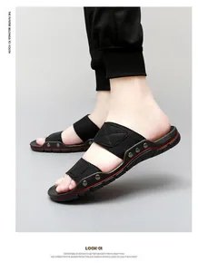 Dettaglio di sandali neri da uomo con borchie metalliche e accenti sulla suola rosso.