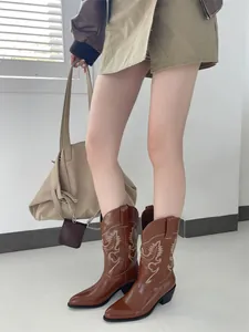 Detailansicht brauner Western-Cowboystiefel mit Blumenstickerei an einem schicken Model.