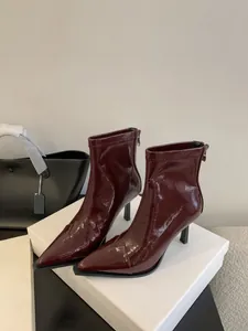 Nahaufnahme von weinroten Lackleder-Stiefeletten mit elegantem Pfennigabsatz und Spitze