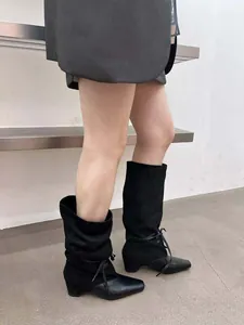 Détail de bottes plissées noires rétro avec bout pointu et design multi-matières
