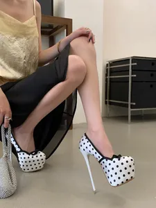 Primer plano de tacones de aguja con plataforma y lunares blancos con un lazo negro