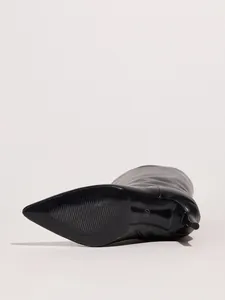Detailed view of the non-slip sole and stiletto heel of a black pointed-toe boot