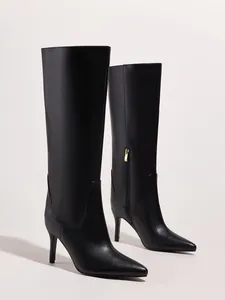 Detailed view of elegant black knee-high pointed toe boots with sleek stiletto heels