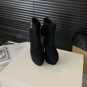 Detalle de botines de plataforma de ante negro con tacón de 16 cm y hebilla metálica