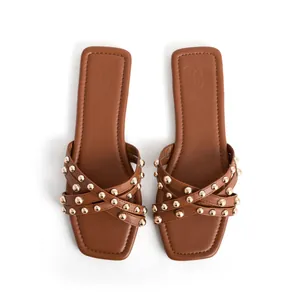 Brown flat sandals with gold studs and cross straps for women's summer fashion beach wear.